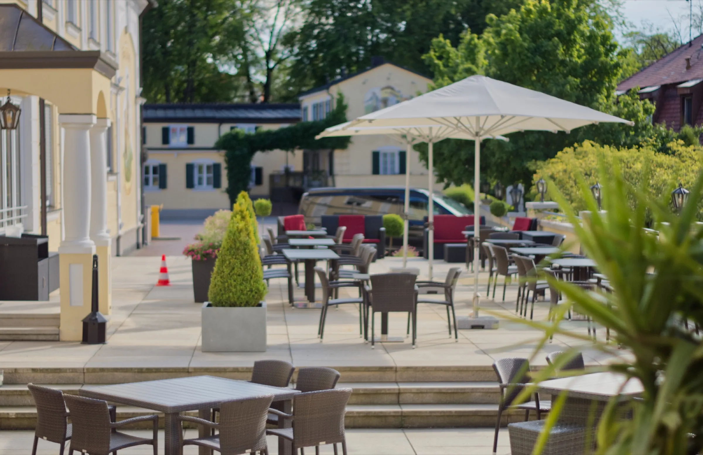Terrasse vor dem Hotel mit Sonnenschirmen und Tischen