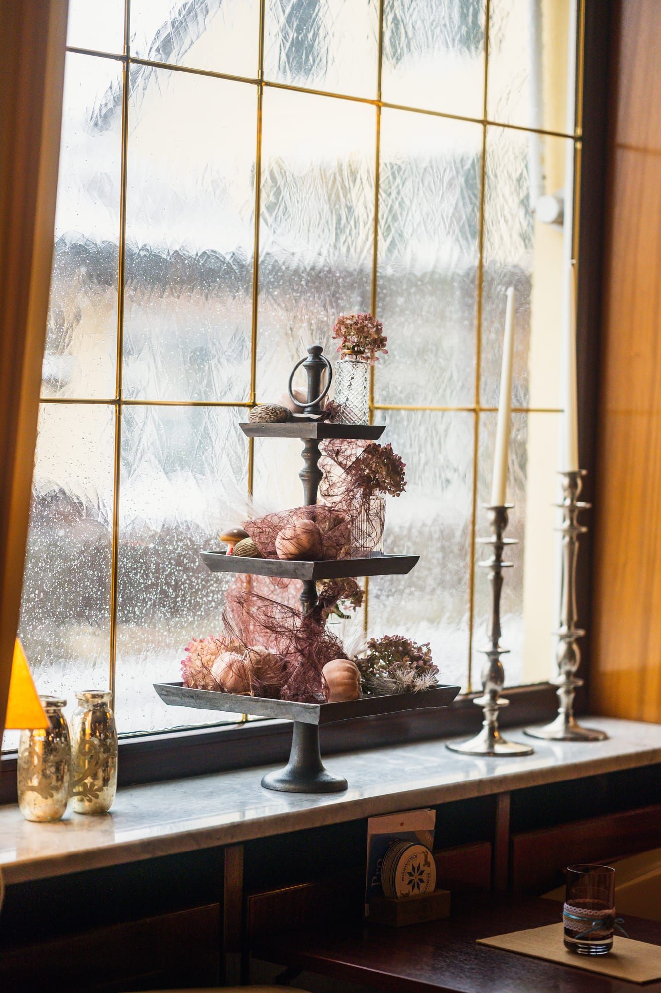 Etagere mit Winterdeko vor einem Fenster mit Schneefall