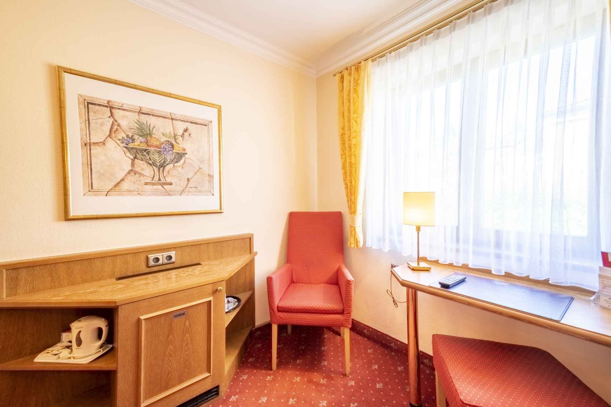 Roter Sessel, Schreibtisch und Bild an der Wand in einem Gästezimmer