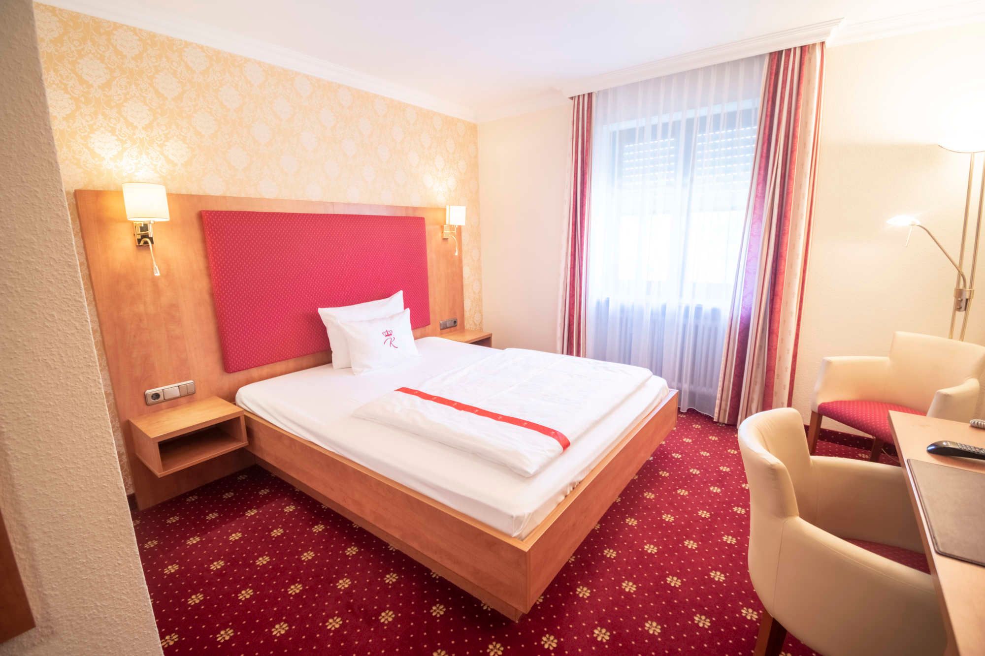Doppelzimmer mit rotem Kopfteil, Sessel und Fenster