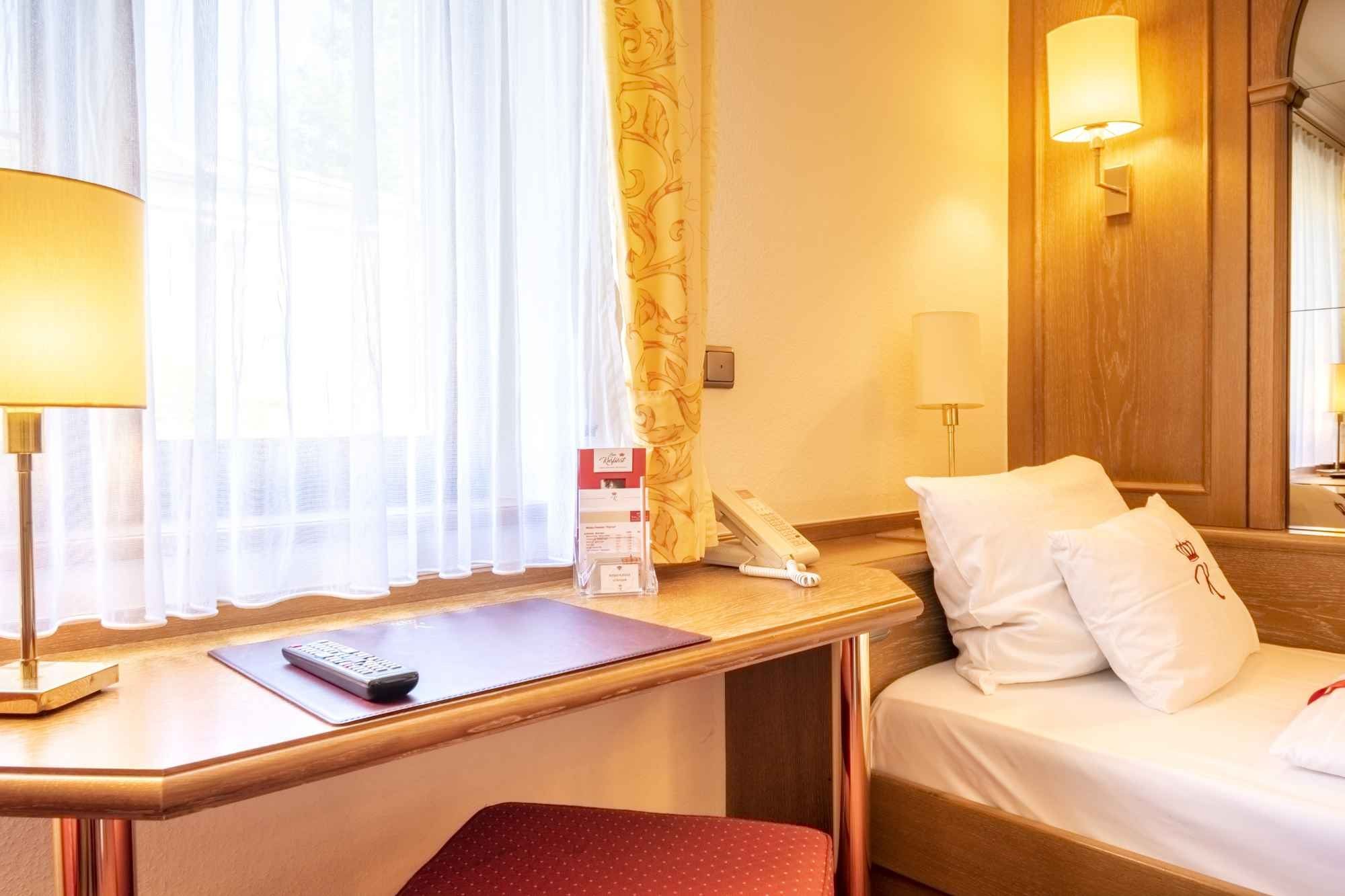 Schreibtisch mit Leselampe vor einem hellen Fenster in einem Gästezimmer