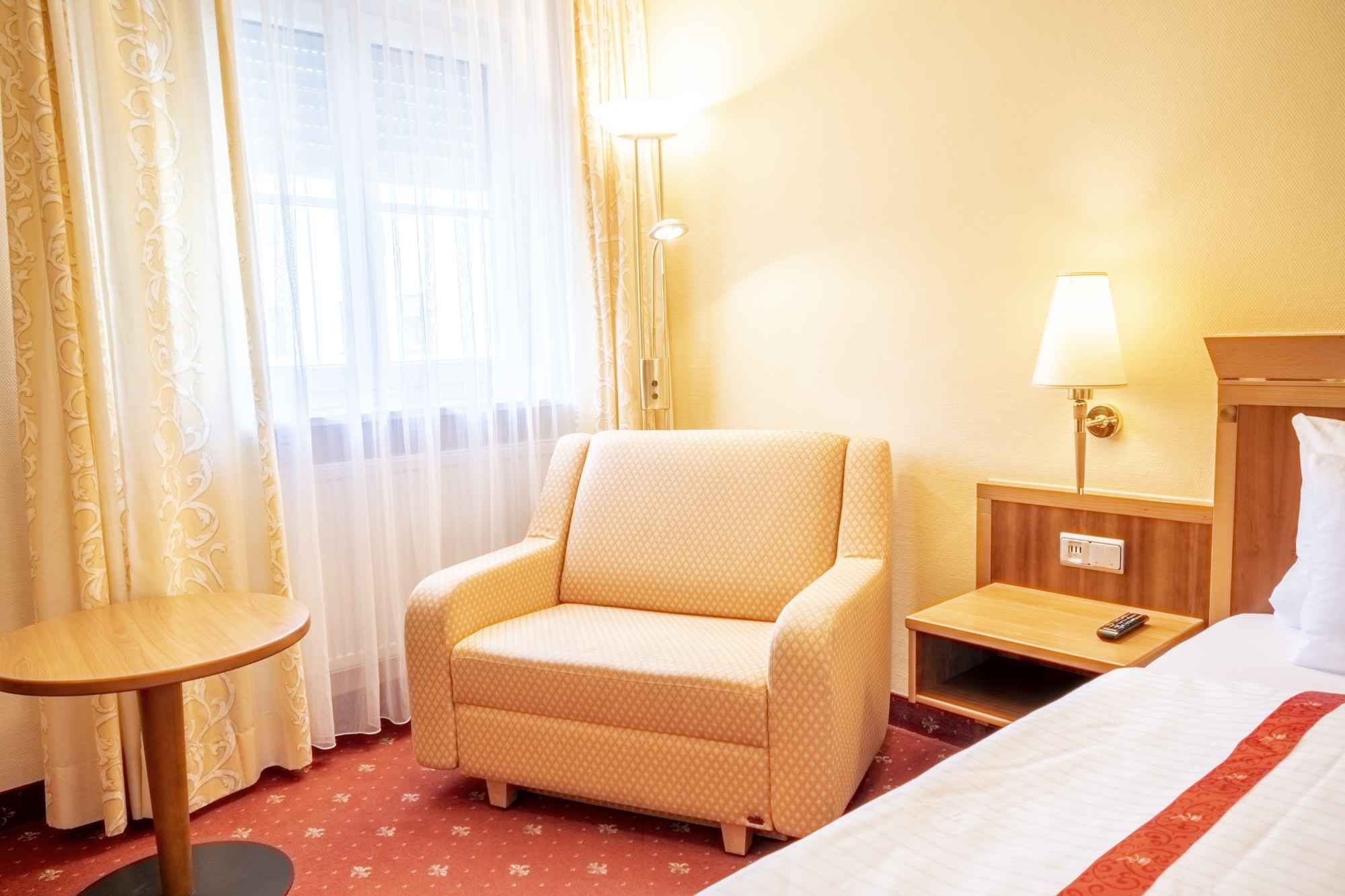 Gepolsterter Sessel und kleiner Tisch am Fenster eines Gästezimmers