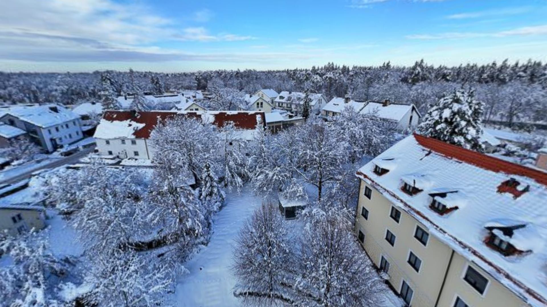 Verschneiter Ort mit Hotelgebäude und Garten, von oben