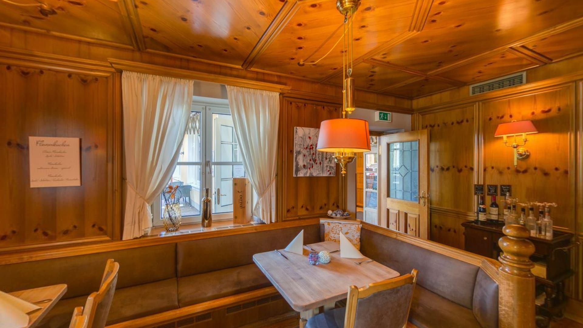 Holzgetäfelte Stube mit Eckbank, Hängelampe und gedecktem Tisch